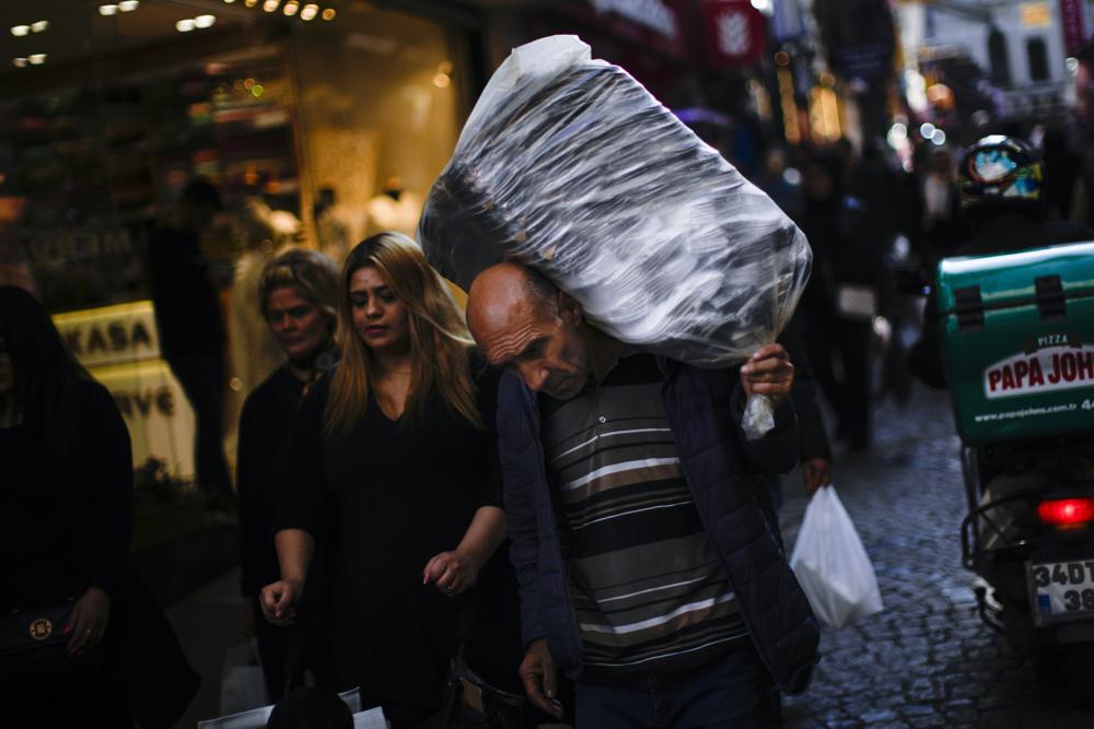  Người đàn ông mang vác hàng hóa trong một khu chợ ở thành phố Istanbul, Thổ Nhĩ Kỳ. Ảnh: AP.